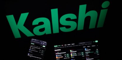 Esta fotografía muestra unas pantallas instaladas que exhiben el logotipo y la página de inicio de Kalshi
