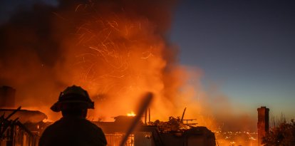 Un bombero lucha contra el incendio Norte Fire mientras este arrasa una casa en San Juan Capistrano, California