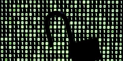 Un candado frente a un código binario en la pantalla de una computadora portátil