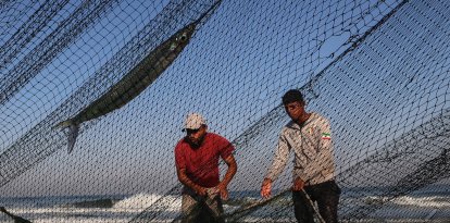 Palestinian fishermen retrieve their catch on the beach in the central Gaza Strip
