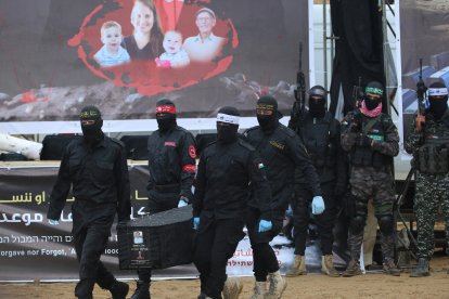 Palestinian terrorists carry one of the coffins as they hand over the bodies of four Israeli hostages