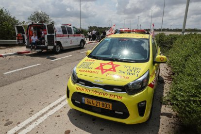 Los servicios de emergencia médica israelíes esperan en una carretera salpicada de barro a las afueras del aeropuerto israelí Ben Gurion tras el impacto de un misil cerca de las instalaciones el 4 de mayo de 2025.
