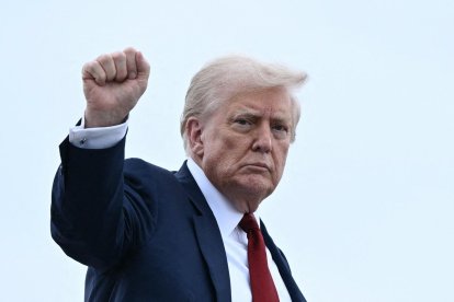 US President Donald Trump pumps his fist as he boards Air Force One at Joint Base Andrews, Maryland, on August 1, 2025. Trump is travelling to New Jersey to spend the weekend at his Bedminster residence. (Photo by Brendan SMIALOWSKI / AFP)