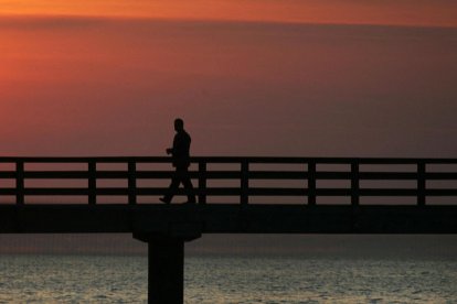 Un hombre solitario camina por un muelle