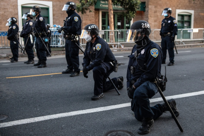 Miembros del departamento de policía de San Francisco se ponen de rodillas en la calle.