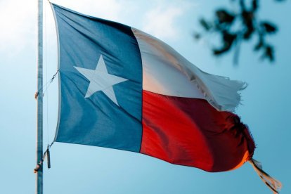 Una bandera texana, deshilachada, ondea al viento.
