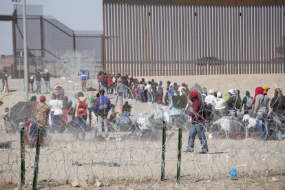 Migrantes en fila intentando cruzar la frontera entre Estados Unidos y México.