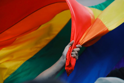 Una mano agarrando la bandera LGBT en la que se incluye a los colectivos trans, gay, bandera.