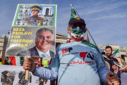 Un manifestante lleva un cartel de apoyo a Reza Pahlavi con su fotografía.