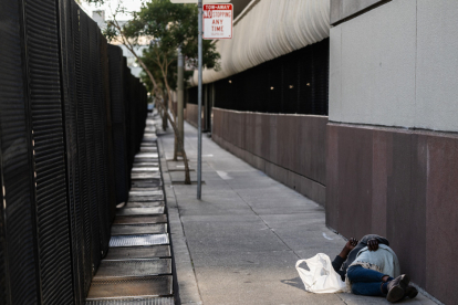 A person sleeps near a security fence setup around the Moscone convention center hosting the Asia-Pacific Economic Cooperation (APEC) leaders' week in San Francisco, California, on November 13, 2023. President Joe Biden this week welcomes Pacific Rim allies to San Francisco, where he will also hold a high-stakes summit with Chinese President Xi Jinping, part of the US leader's effort to confront Beijing's growing clout. (Photo by ANDREW CABALLERO-REYNOLDS / AFP)