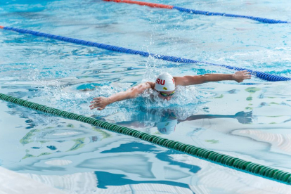 Deportista en una piscina nadando mariposa.