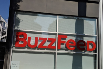 Foto de una oficina de BuzzFeed desde afuera donde se ven el nombre de la empresa en rojo contra la ventana.