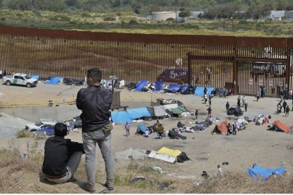 Migrantes frente a una valla en la frontera sur.