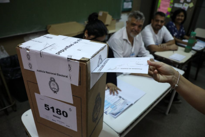 Imagen un votante introduciendo un voto dentro de una urna en el balotaje argentino.