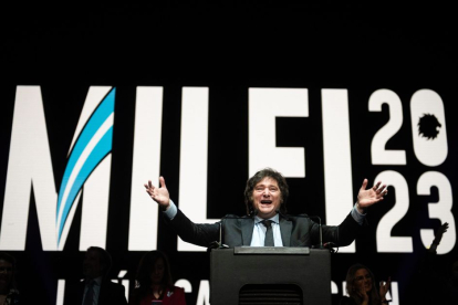 El candidato presidencial argentino Javier Milei habla en un estrado delante de una gigantografía con su nombre y el año 2023.