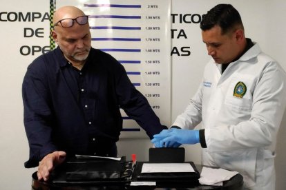 A picture released by the Colombian Interpol shows Colombian-Italian former paramilitary chief Salvatore Mancuso (L) with a member of the forensic police upon his arrival at the El Dorado International Airport in Bogota
