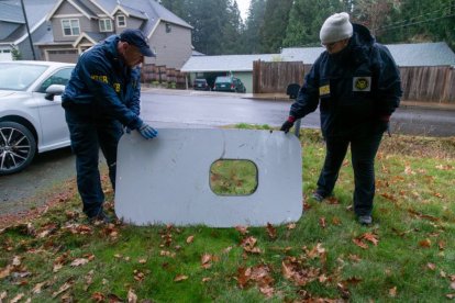 Imagen de agentes de la FAA recuperando la pieza de la ventana de emergencia que apareció en el patio trasero de un vecino de Portland tras el accidente de Alaska Airlines.