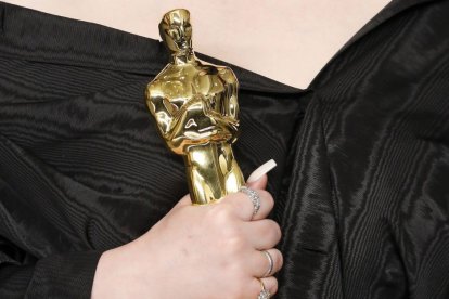Imagen de la mano de Billie Eilish sosteniendo un premio Óscar en la ceremonia celebrada en el año