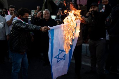 Manifestantes pro Palestina queman una bandera de Israel.