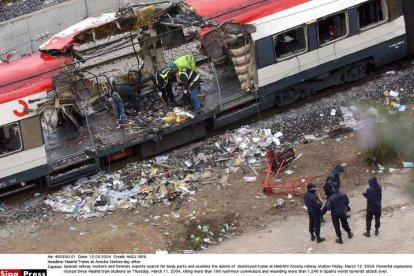 Trabajadores ferroviarios españoles y expertos forenses buscan restos mortales y examinan los escombros de los trenes destruidos en la estación de Atocha de Madrid el viernes 12 de marzo de 2004.