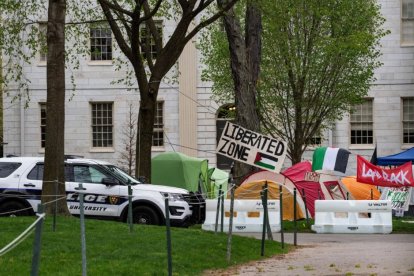 Un coche patrulla de la policía se encuentra junto a tiendas de campaña y carteles que llenan Harvard Yard