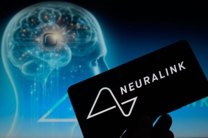 Imagen de una mano sosteniendo un teléfono con el logo de Neuralink sobre otra imagen de un cerebro humano generado artificialmente.