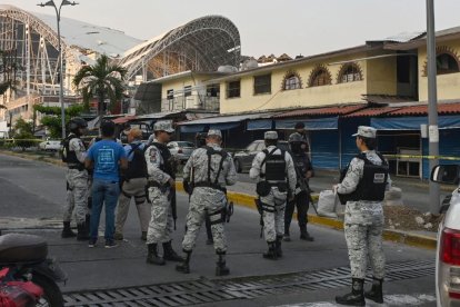 Miembros de la Guardia Nacional montan guardia mientras investigadores de la fiscalía, la policía estatal y personal forense trabajan en la escena del crimen donde cinco personas fueron asesinadas en un mercado de artesanías durante una ola de violencia que golpea el puerto turístico de Acapulco, estado de Guerrero, México, el 23 de mayo de 2024.
