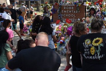 Los dolientes se reúnen en un monumento de flores en la Escuela Primaria Robb en Uvalde, Texas, el lunes 30 de mayo de 2022. Un tiroteo masivo días antes dejó 19 niños y dos adultos muertos en la escuela primaria.