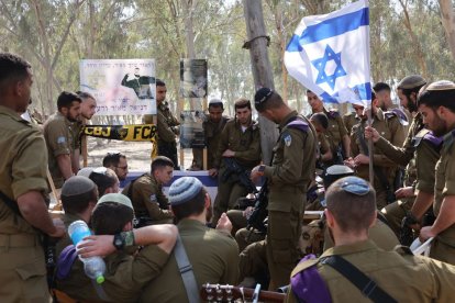 Soldados israelíes visitan un monumento conmemorativo con los retratos de las personas cautivas o muertas en el ataque de Hamás contra el festival de música Supernova el 7 de octubre, en el lugar donde se celebró el festival, cerca del kibutz Reim, en el sur de Israel, el 7 de abril de 2024.