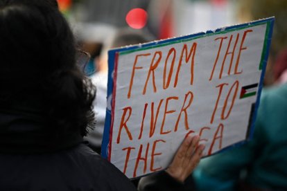 Un manifestante muestra un cartel con la inscripción "Del río al mar"-