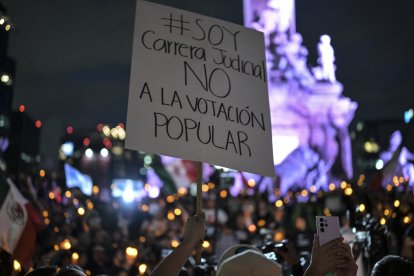 Un manifestante sostiene un cartel contra la reforma judicial de AMLO