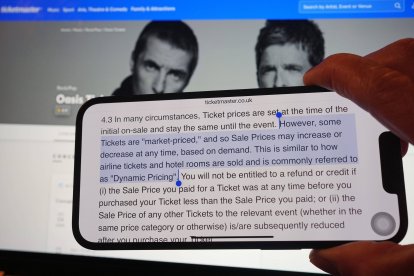 A section of Ticketmaster's purchase policy explaining "Dynamic Pricing" - found on the company's website - is highlighted on a phone, with the Tickemaster website displayed in the background, showing the options for purchasing Oasis tickets, in London. Picture date: Monday September 2, 2024.