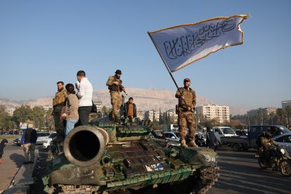 Terroristas islamistas una bandera blanca de la yihad sobre un tanque en Damasco tras derrocar al régimen de Asad