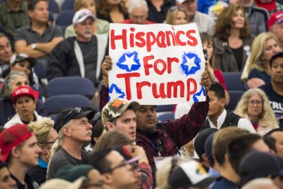 Un hombre sostiene un cartel en el que se lee "Hispanos por Trump"