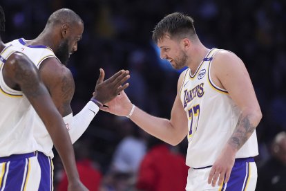 El escolta de Los Angeles Lakers Luka Doncic, a la derecha, es felicitado por el alero LeBron James tras anotar durante la primera mitad de un partido de baloncesto de la NBA contra Los Angeles Clippers.