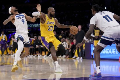 El alero de los Lakers de Los Ángeles LeBron James (23) regatea al escolta de los Timberwolves de Minnesota Nickeil Alexander-Walker (9) y al pívot Naz Reid (11) durante la primera parte del segundo partido de la primera ronda de los playoffs de la NBA en Los Ángeles.