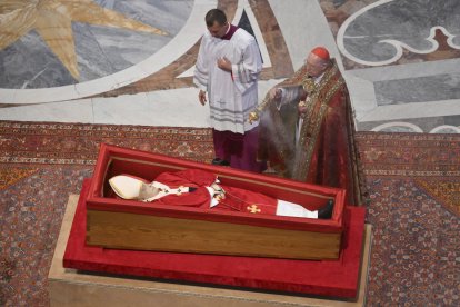 El cardenal camarlengo Kevin Joseph Farrell, a la derecha, flanqueado por el maestro de ceremonias vaticano monseñor Krzysztof Marcjanowicz inciensa el cuerpo del papa Francisco en el interior de la basílica de San Pedro del Vaticano, el miércoles 23 de abril de 2025, donde reposará durante tres días.