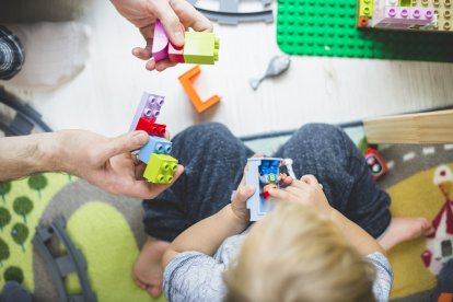 A boy plays with Legos with his father.
