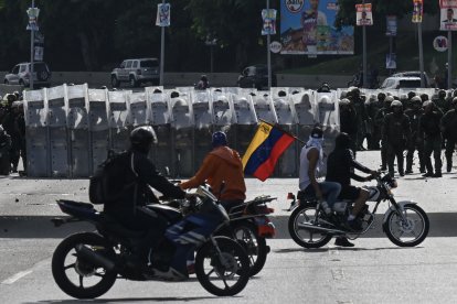 Manifestantes conducen sus motocicletas frente a miembros de la Guardia Nacional Bolivariana durante una protesta contra el gobierno de Nicolás Maduro en Caracas