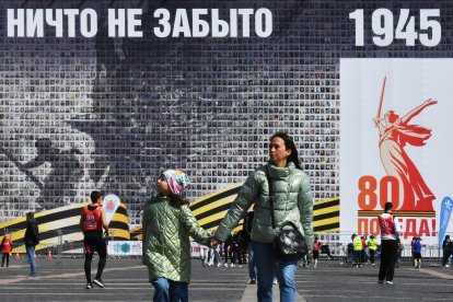 Un grupo de personas pasa junto a una pancarta gigante de "Izar una bandera sobre el Reichstag".