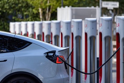 Coches eléctricos se enchufan a una estación de carga Tesla en una oficina (Archivo)