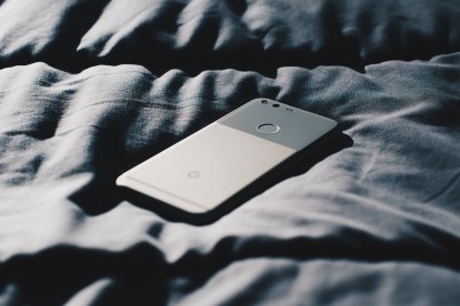 A man turns his cell phone upside down to avoid distractions before going to sleep.