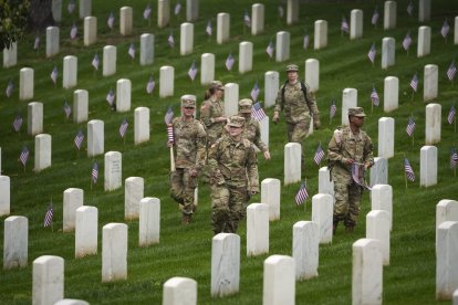 Soldados colocan banderas en las tumbas de los caídos en el Cementerio de Arlington