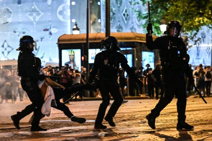 Agentes de la policía antidisturbios detienen a una persona durante las celebraciones en París