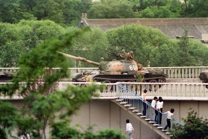 Varios espectadores chinos huyen mientras un soldado les amenaza con una pistola el 5 de junio de 1989, cuando los tanques tomaron posiciones en los cruces clave de Pekín, junto al complejo diplomático. La muerte el 15 de abril del ex líder del partido comunista Hu Yaobang desencadenó una serie de protestas prodemocráticas. En una demostración de fuerza, los dirigentes chinos descargaron su furia y frustración contra los estudiantes disidentes y sus partidarios prodemocráticos. Varios centenares de personas murieron y miles resultaron heridas cuando los soldados irrumpieron en la plaza de Tiananmen durante una violenta represión militar que puso fin a seis semanas de manifestaciones estudiantiles, conocidas como el movimiento de la Primavera de Pekín. Según Amnistía Internacional, cinco años después del aplastamiento del movimiento prodemocrático chino, "miles" de presos seguían en la cárcel.