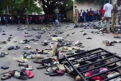Aficionados junto a zapatos abandonados y una barrera caída tras una estampida durante las celebraciones, un día después de la victoria del Royal Challengers Bengaluru en la Indian Premier League (IPL) Twenty20 final de cricket, fuera del estadio M. Chinnaswamy en Bengaluru el 4 de junio de 2025. Al menos 11 personas murieron en una estampida el 4 de junio, cuando una multitud abarrotada celebraba la victoria de su equipo local de críquet en la ciudad india de Bengaluru, informó el ministro principal del estado. (Foto de AFP)