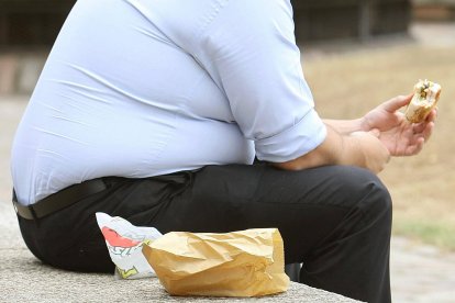 Una persona obesa comiendo una hamburguesa