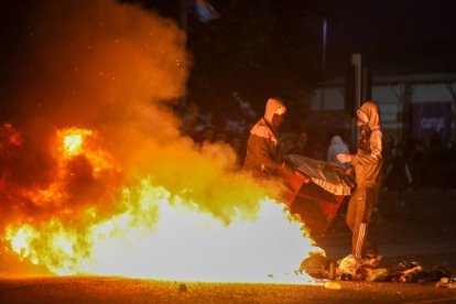 Manifestantes enmascarados avivan una hoguera durante manifestaciones antiinmigración en Ballymena