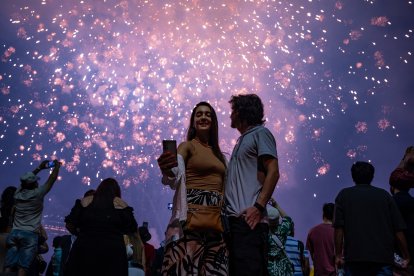 Una mujer se toma una selfie mientras los fuegos artificiales iluminan el cielo