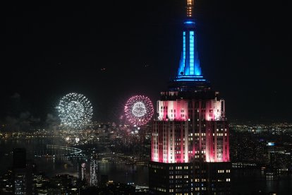 La cima del Empire State Building se ilumina de rojo, blanco y azul mientras los fuegos artificiales estallan sobre el horizonte de Manhattan durante las celebraciones del 4 de Julio